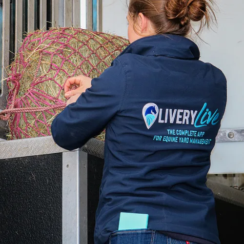 Image shows a lady with a bundle of hay. Image depicts our livery yard management app features