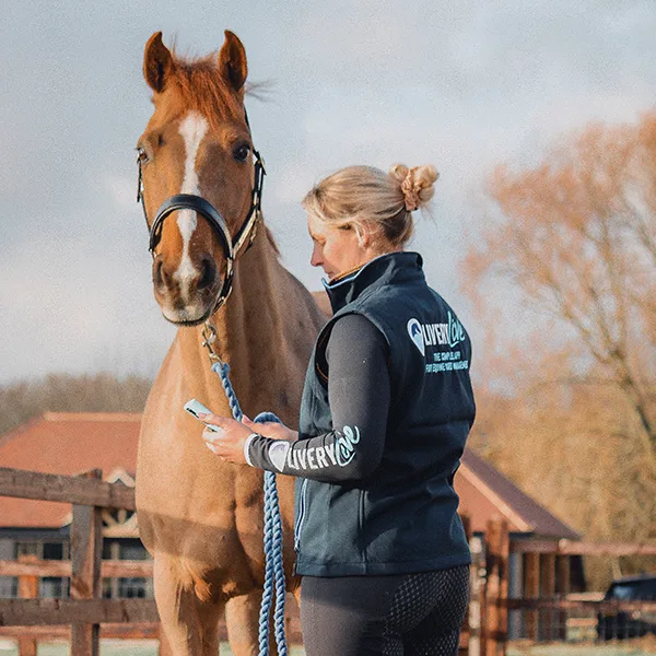 Image shows a lady with a horse accessing Arena Booking Software on her phone app
